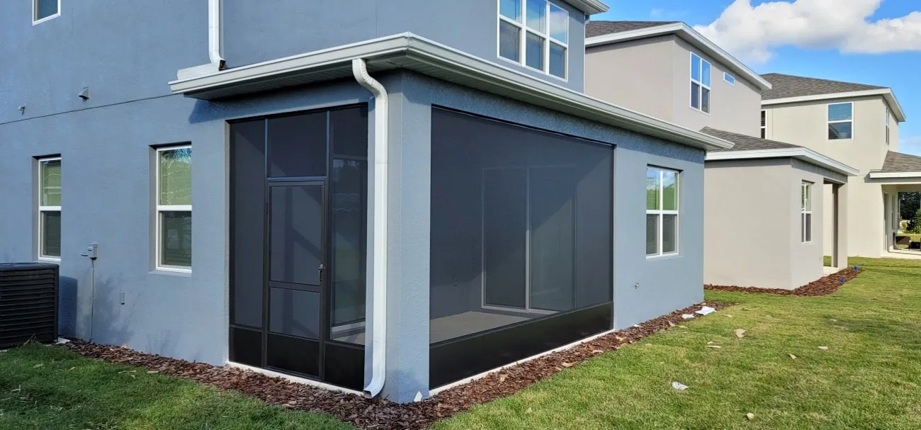 Screened patio enclosure and white gutter with downspout on a gray two-story Florida home