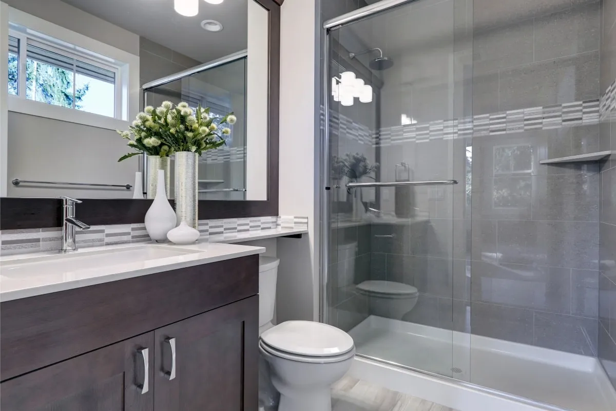 Bathroom with dark wood vanity, mosaic accent tile, and glass sliding shower door