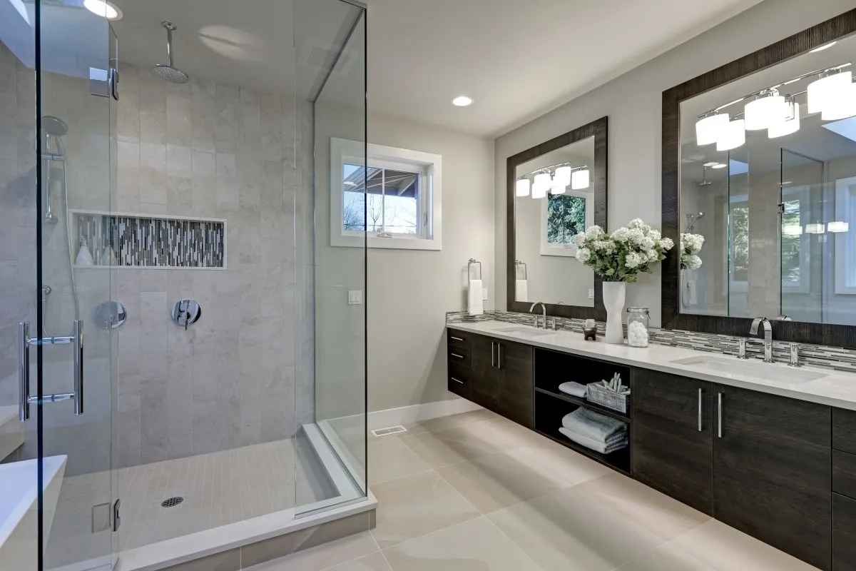 Master bathroom with glass corner shower and dark double vanity with framed mirrors