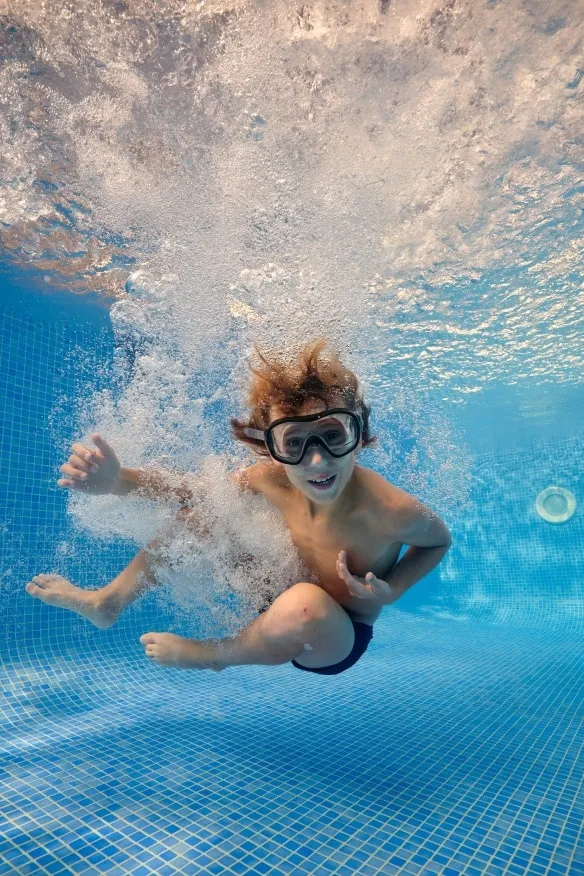 Child swimming underwater in a remodeled pool