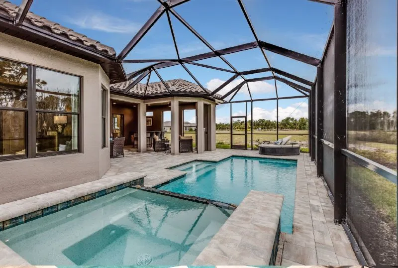 Clear view pool enclosure with modern lanai design, spa, and paver deck in a Florida home