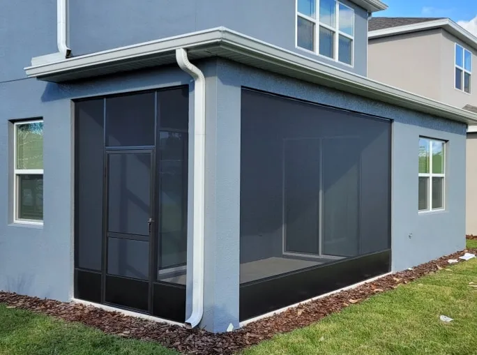 Corner screened porch with aluminum door and dark mesh on a two-story Florida home