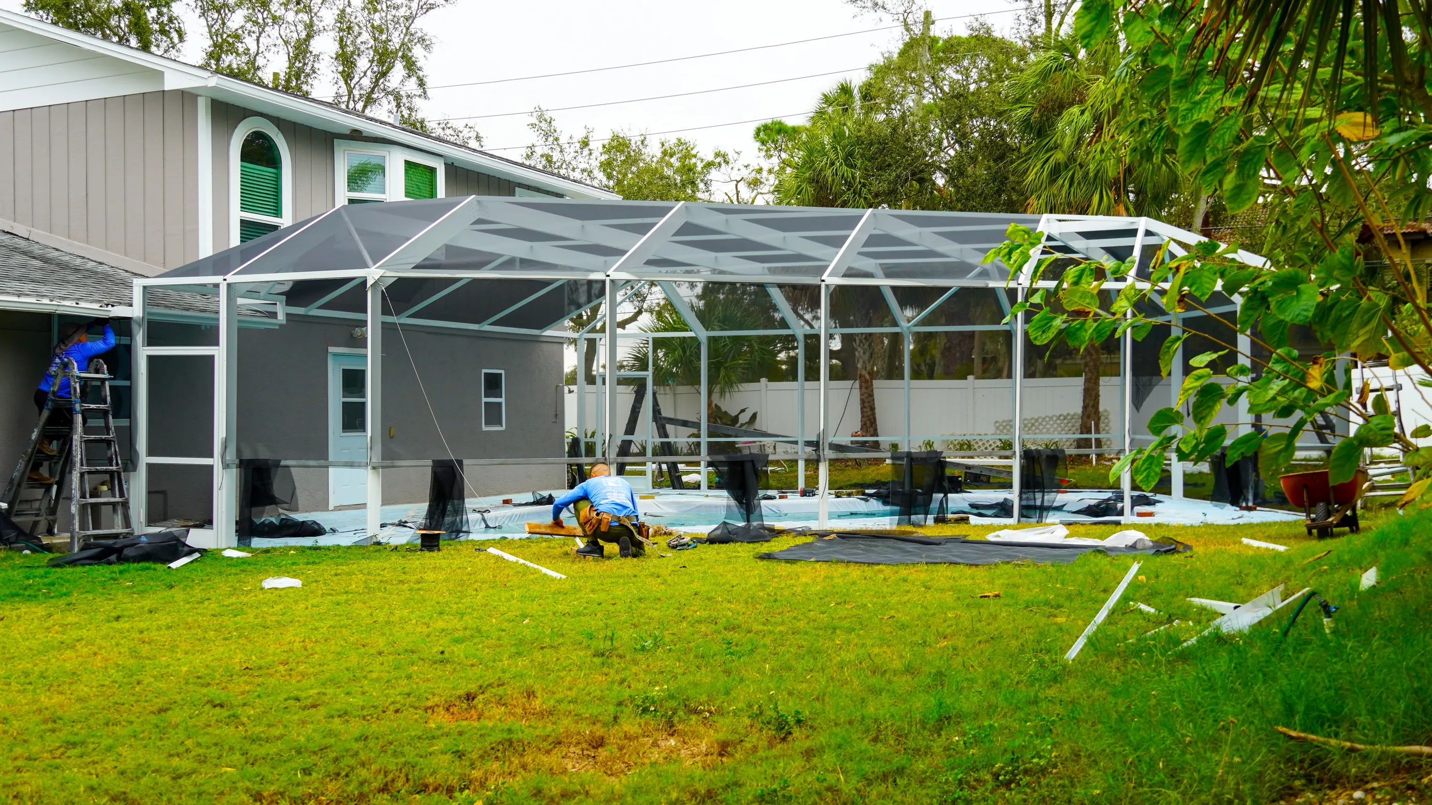Forge Point crew installing a new screen enclosure over a Florida pool, with the aluminum frame up and the first panels going in