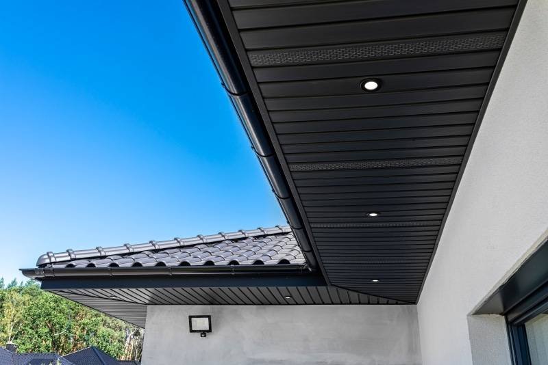 Black aluminum soffit panels with recessed lights and gutter under the roofline of a modern home