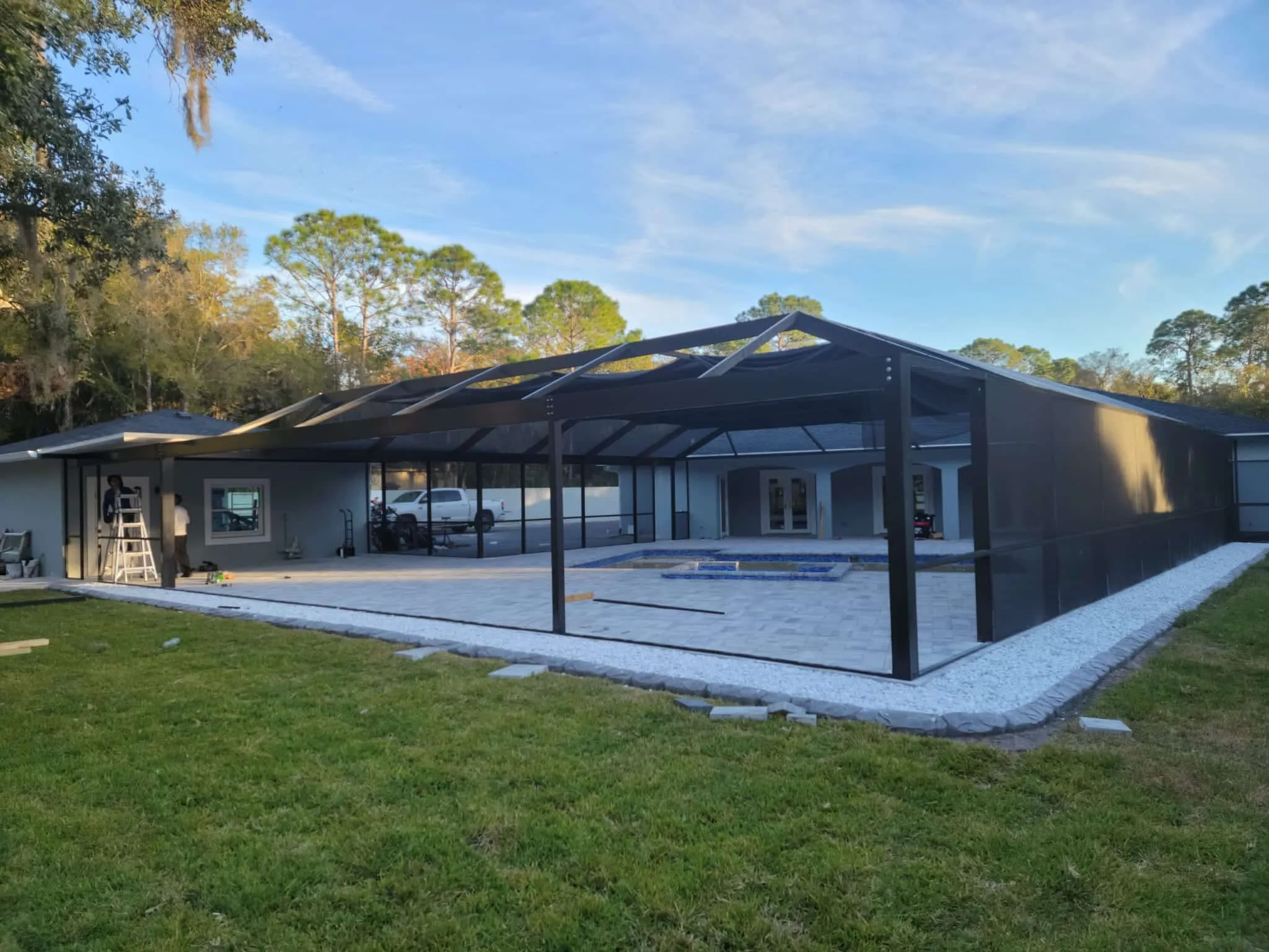 Completed gable pool cage frame with black screen mesh on the walls before the pool is finished