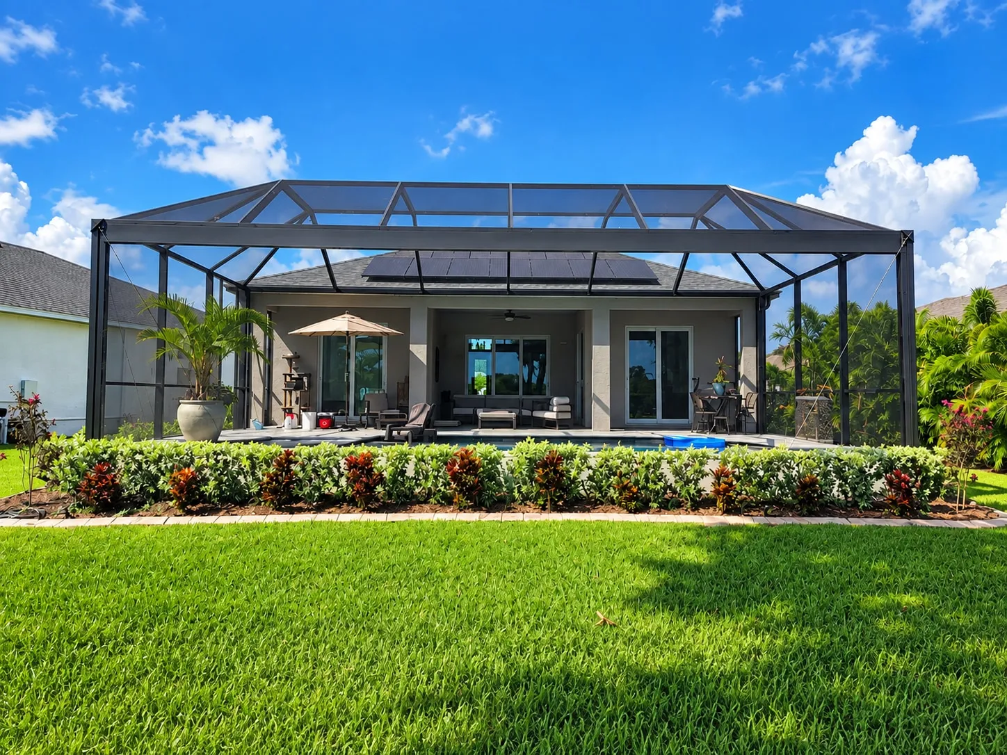 New screen enclosure built over a pool and lanai at the back of a Florida home, seen from the lawn