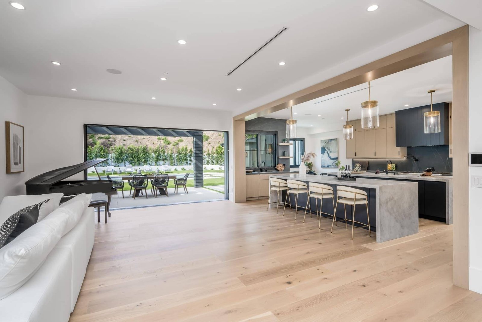 Open-plan remodeled interior with oak flooring, marble kitchen island, and glass wall to a patio