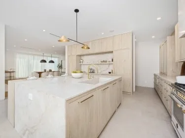 Minimalist kitchen remodel with marble waterfall island and light wood cabinetry