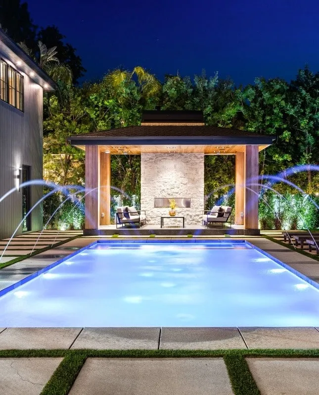 Modern rectangular pool with raised spa and stone water wall in Florida