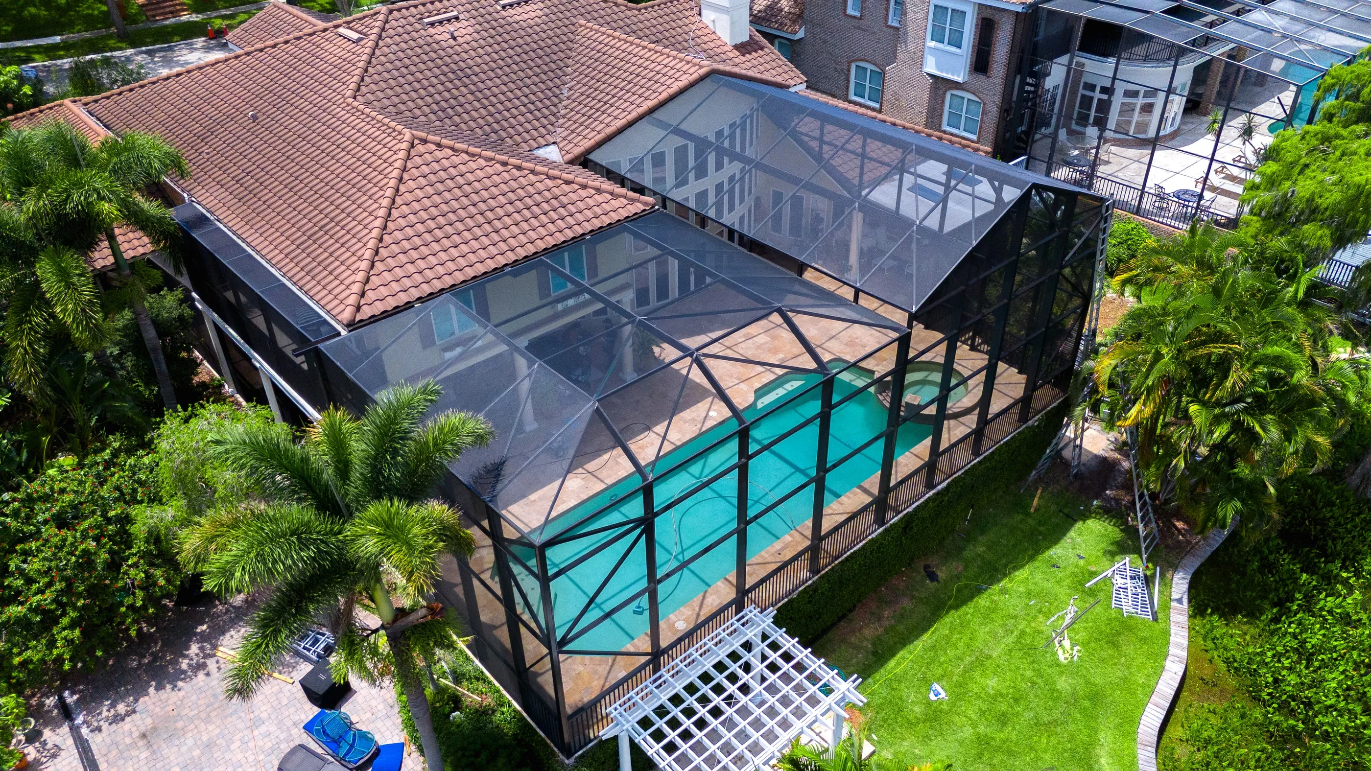 Aerial view of a finished panoramic pool enclosure with wide dark aluminum spans over a pool and spa at a Florida home