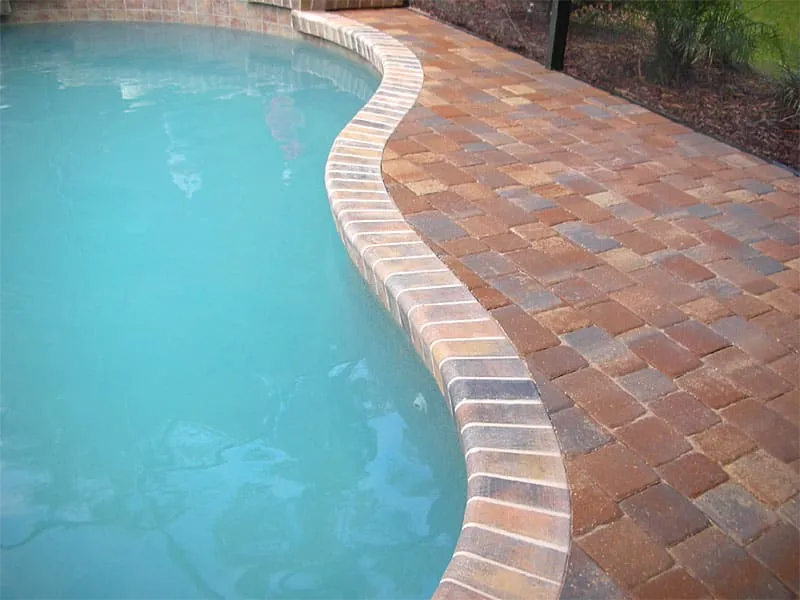 Curved pool edge with multicolor brick pavers and matching brick coping