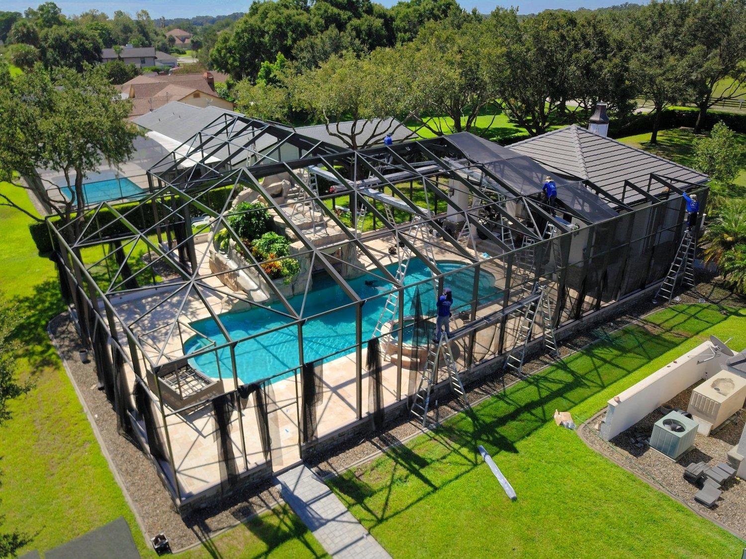 Rescreening crew installing new mesh panels on a large pool cage in Florida