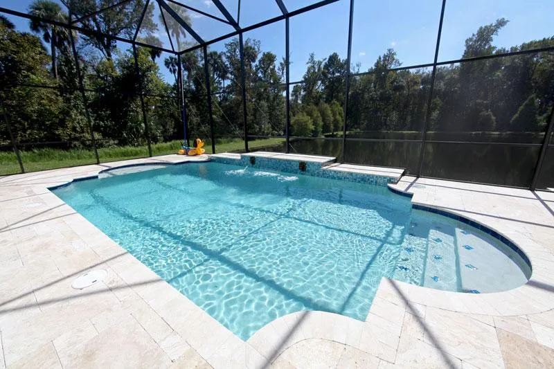Travertine paver deck around a screened pool overlooking a pond