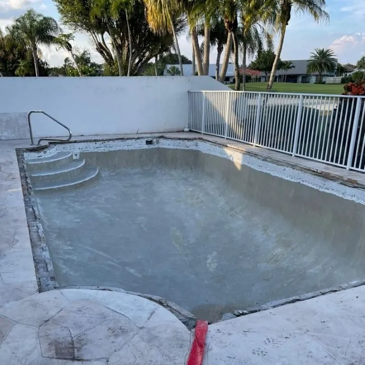 Worn-out residential pool before resurfacing and deck renovation in Florida, showing surface damage and outdated finishes.