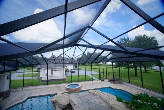 Inside a freshly rescreened pool enclosure with pool, raised spa, and lawn views