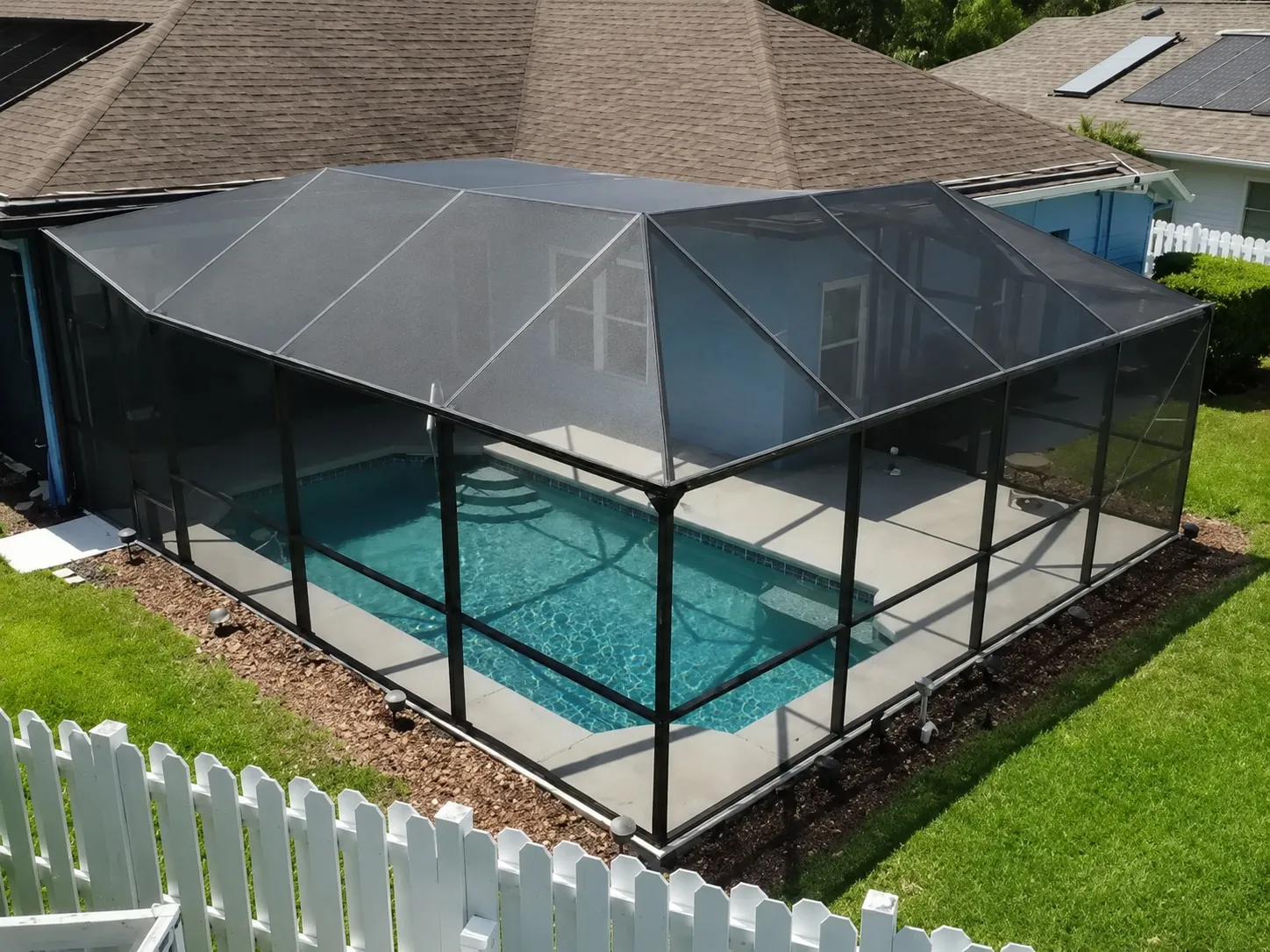 Restored pool cage with fresh bronze paint and new screens around a backyard pool