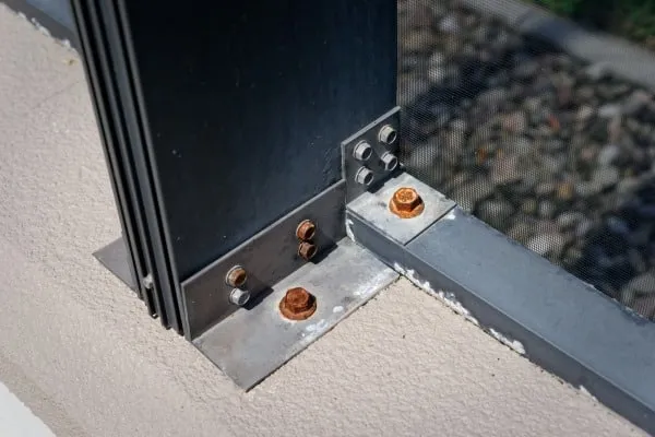Rusted screws at the base of an aluminum pool cage post before stainless steel hardware replacement