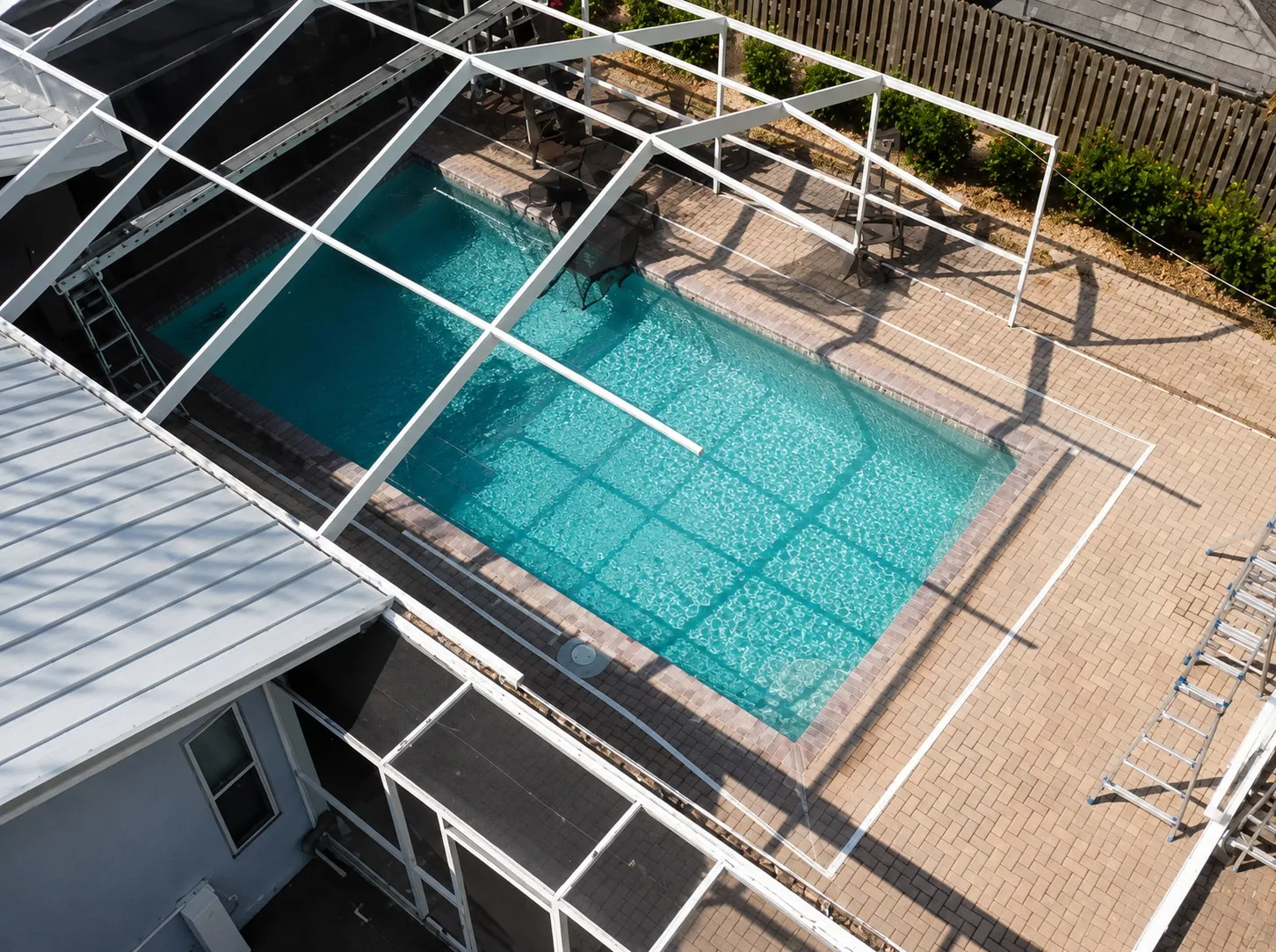 Damaged pool screen enclosure with peeling paint and torn screens before repair
