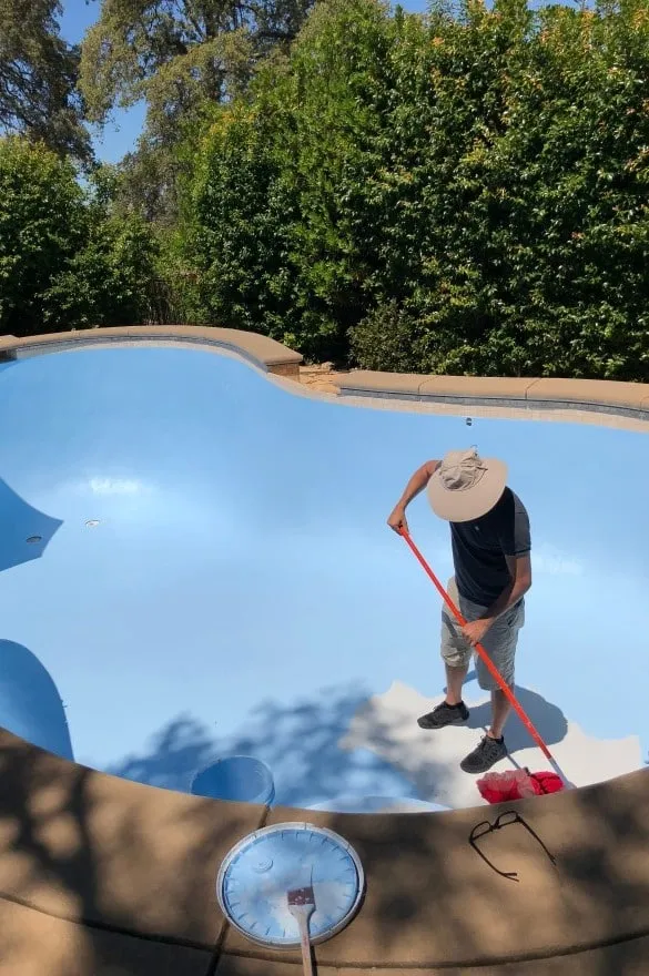 Technician cleaning a pool during resurfacing work