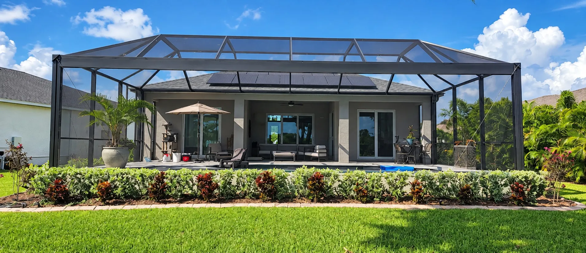 Clear View screen enclosure seen from the lawn, its wide panels spanning the back of a Florida home with almost no vertical bars