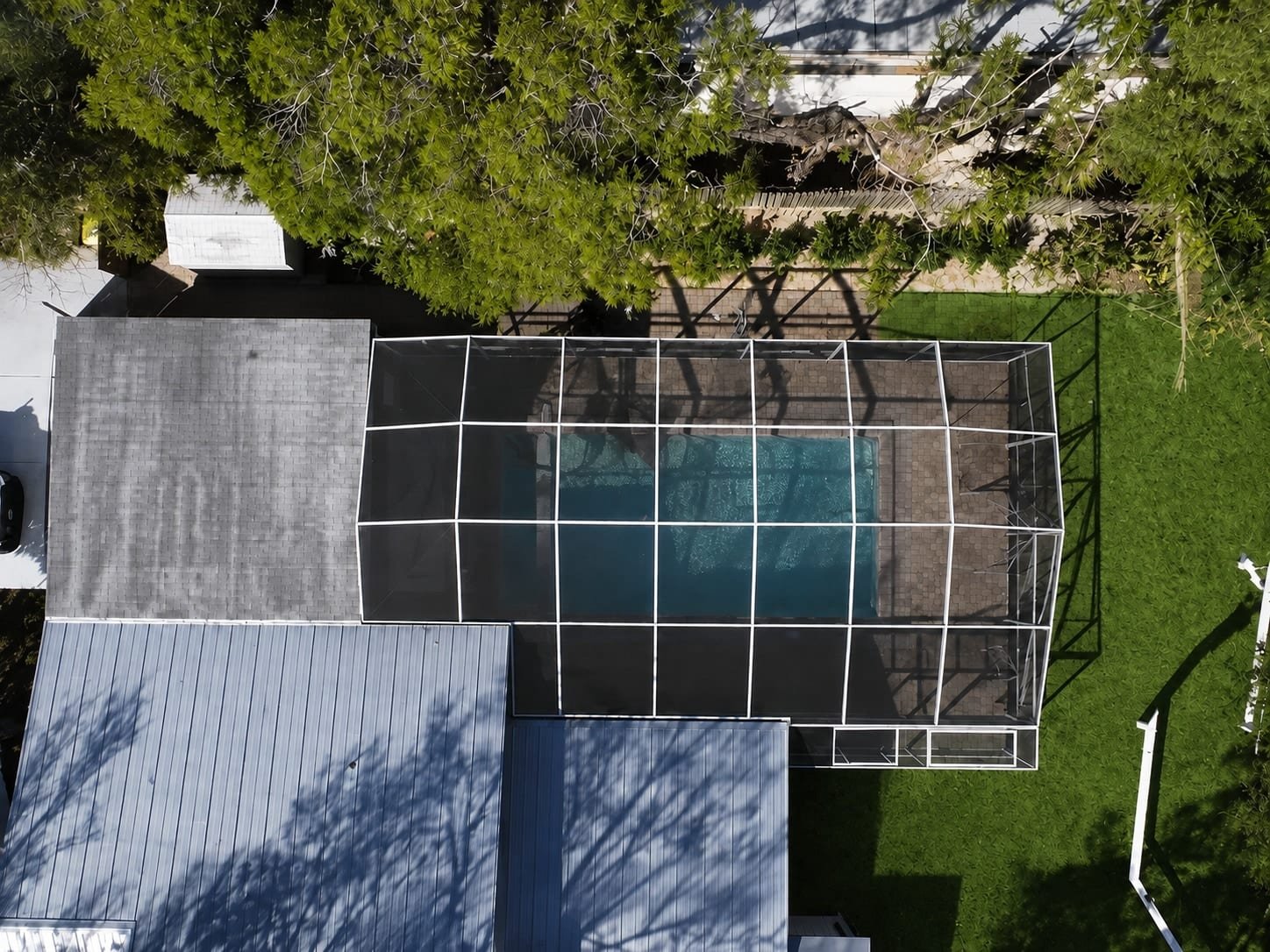 Aerial view of a completed screen enclosure attached to a residential structure with surrounding lawn and trees.